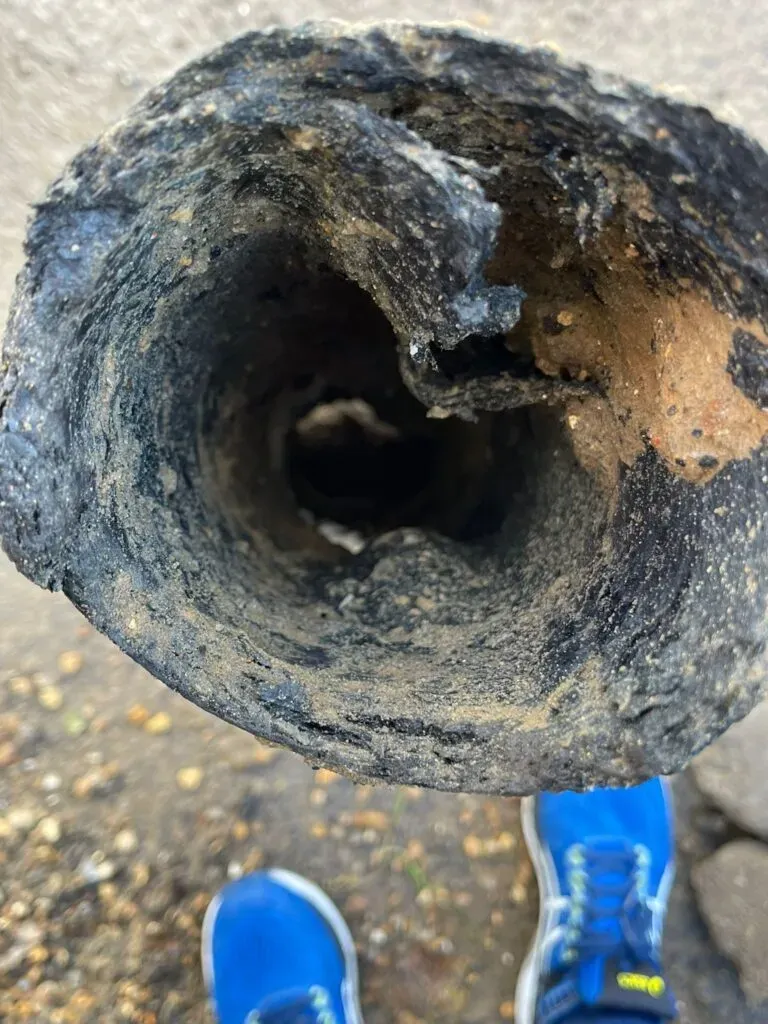 Severely damaged and deformed pitch fibre drain pipe showing internal collapse and a blocked lumen, needing repair or relining.